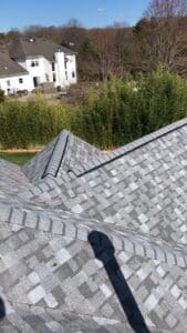 Gray shingled roof ridge with neighborhood view