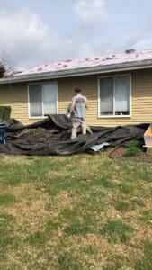 Worker removing shingles from ranch-style house