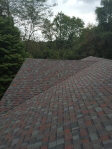 Roofer kneeling with tools near vent