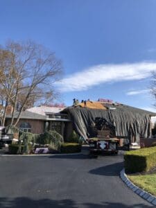 Large house roof replacement with tarp and truck