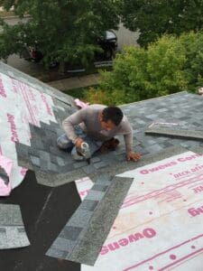 Worker installing asphalt shingles on roof