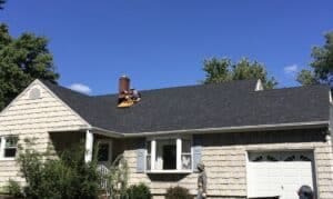 Roofers working on chimney with dark shingles