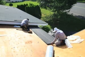 Roofers installing shingles on residential roof