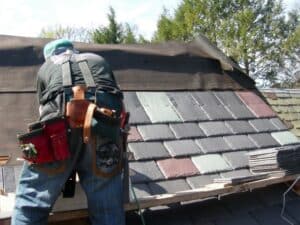 Roofer installing slate tiles with tool belt