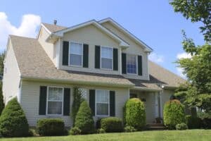 Two story beige house with dormered roof