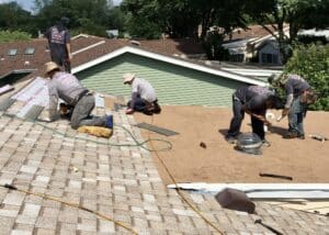 Roofers installing asphalt shingles on house