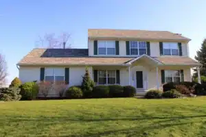 Two-story suburban house with white siding and green shutters.